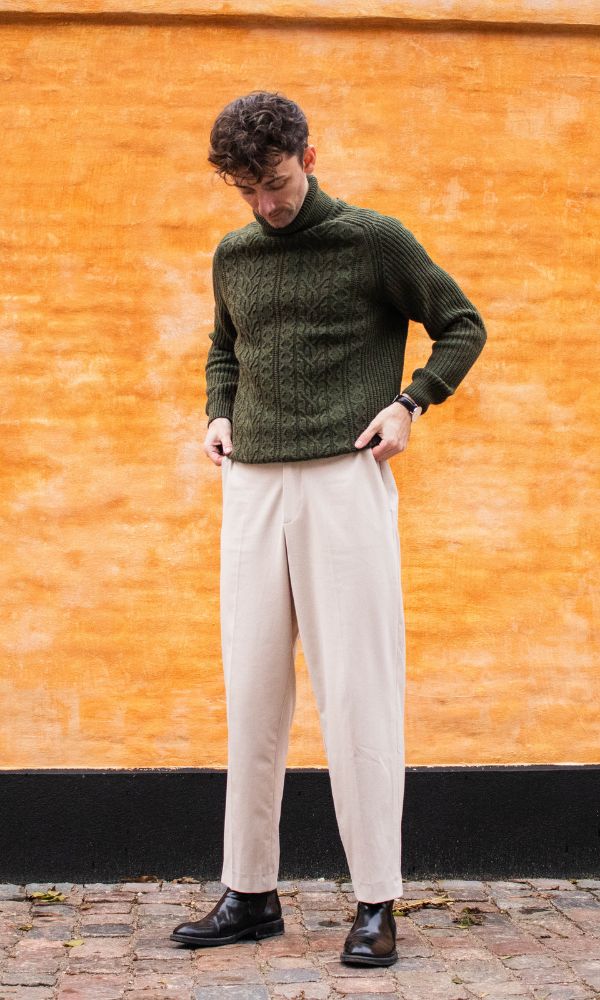 Palermo Pants parret med mørkegrøn turtleneck og sorte læderstøvler foran orange mur