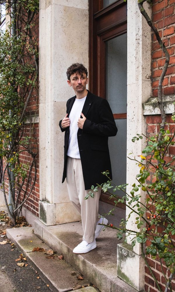 Palermo Pants sat sammen med hvide sneakers og sort frakke ved opgang til rød murstensbygning